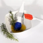 Blue and red Silikomart silicone pastry brushes beside rosemary and oil