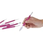 Hand holding a fuchsia Silikomart Wonder Cakes tool for detailed cake modelling