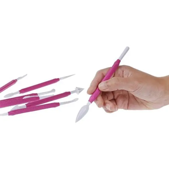 Hand holding a fuchsia Silikomart Wonder Cakes tool for detailed cake modelling